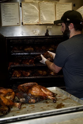 A volunteer pulling smoked turkeys from the smoker racks